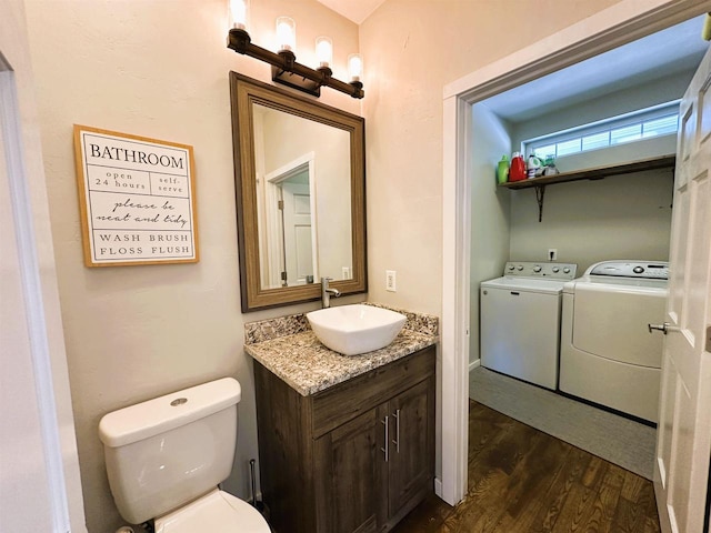 bathroom featuring washing machine and dryer, toilet, vanity, and wood finished floors