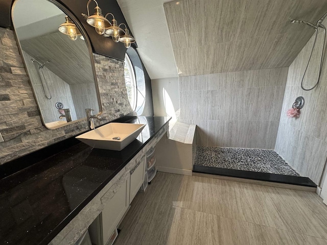 bathroom featuring a tile shower, vanity, and vaulted ceiling