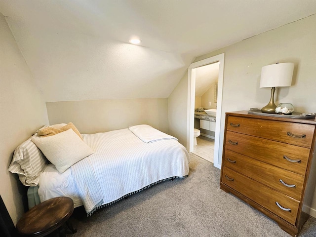 carpeted bedroom featuring lofted ceiling and connected bathroom