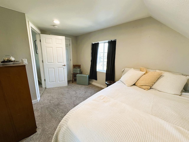 carpeted bedroom featuring lofted ceiling and baseboards