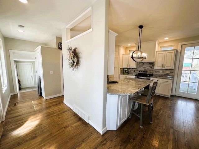 kitchen with decorative backsplash, dark wood finished floors, stainless steel electric range, and visible vents