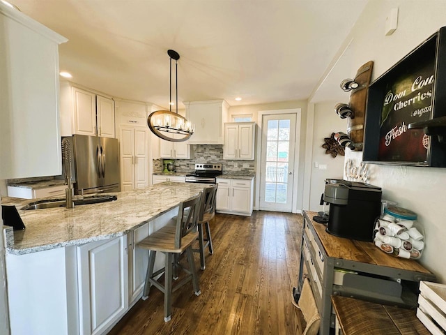 kitchen with backsplash, dark wood-type flooring, light stone counters, a peninsula, and stainless steel appliances