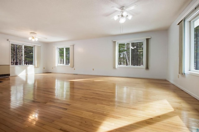 spare room with ceiling fan, baseboards, and light wood-style flooring