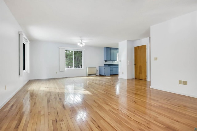 unfurnished living room featuring a ceiling fan, light wood-style floors, and baseboards