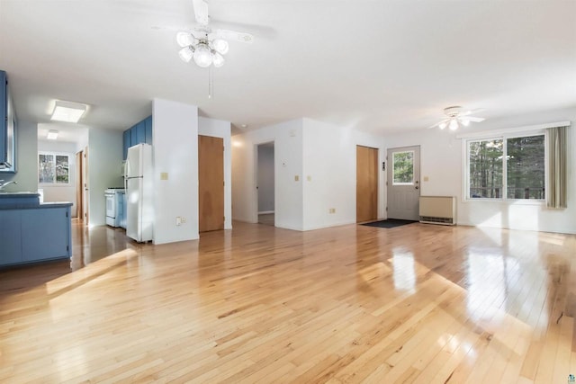 unfurnished living room with a sink, light wood-style flooring, and ceiling fan