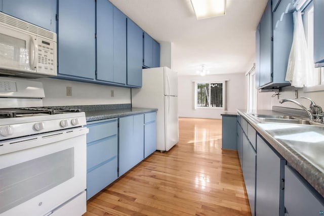 kitchen with blue cabinetry, white appliances, a sink, and light wood finished floors