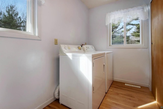 laundry area featuring laundry area, baseboards, independent washer and dryer, and light wood-type flooring