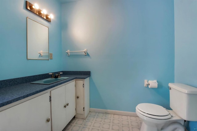 half bathroom with tile patterned floors, toilet, vanity, and baseboards