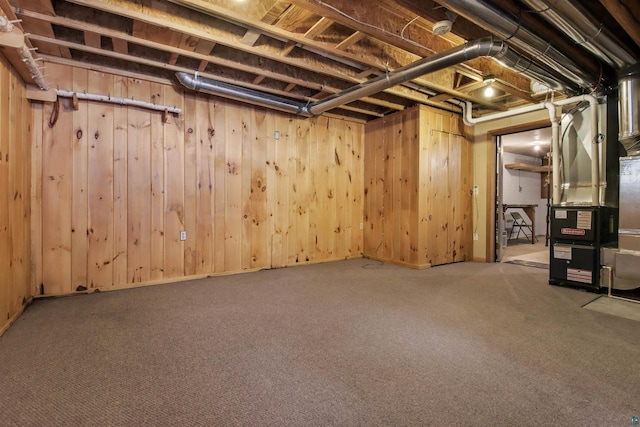 unfinished basement featuring heating unit, wooden walls, and carpet flooring