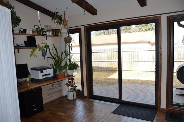 doorway with beam ceiling and brick floor