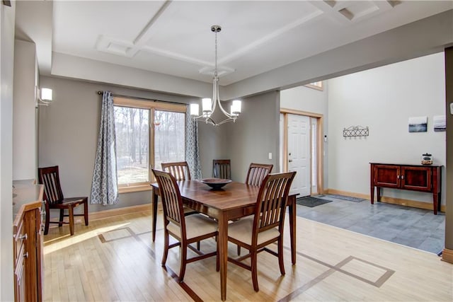 dining room featuring a notable chandelier, baseboards, coffered ceiling, and light wood-style flooring