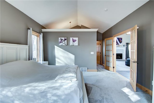 carpeted bedroom with visible vents, baseboards, lofted ceiling, a fireplace, and french doors