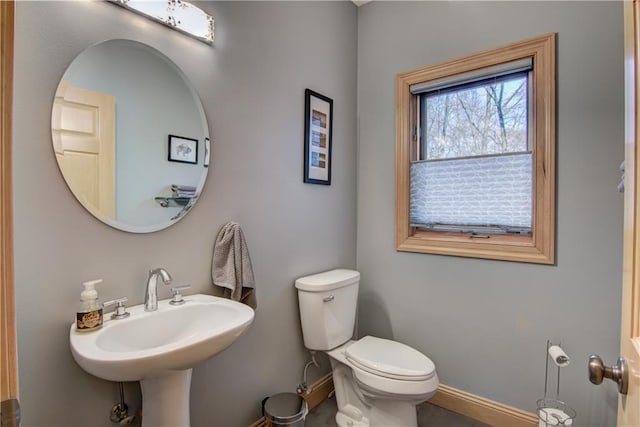 half bathroom featuring toilet, baseboards, and a sink