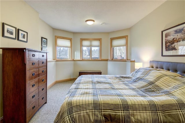 bedroom featuring multiple windows, light colored carpet, and baseboards