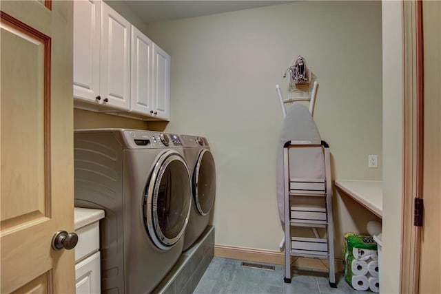 clothes washing area featuring separate washer and dryer, cabinet space, visible vents, and baseboards