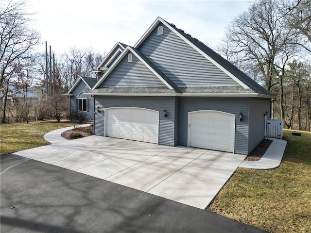 view of side of home with a yard, a garage, driveway, and roof with shingles