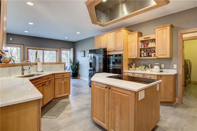 kitchen featuring a sink, black appliances, light countertops, washing machine and dryer, and a center island