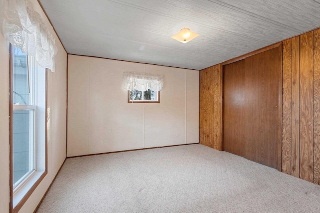 carpeted empty room with wooden walls