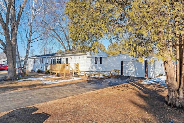 view of front facade featuring an outbuilding, driveway, a wooden deck, and a garage