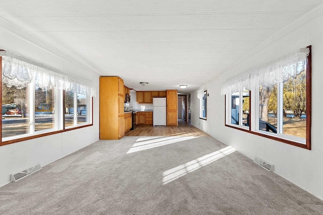 unfurnished living room featuring visible vents and light colored carpet