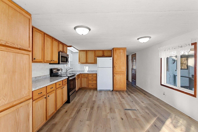 kitchen featuring light countertops, light wood-style flooring, appliances with stainless steel finishes, and a sink