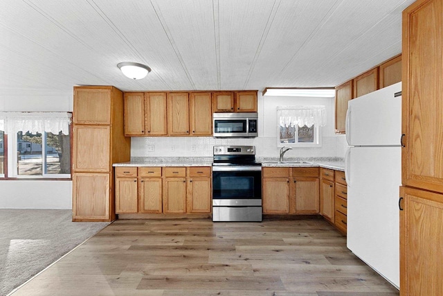 kitchen featuring wood ceiling, light countertops, light wood-style flooring, appliances with stainless steel finishes, and a sink