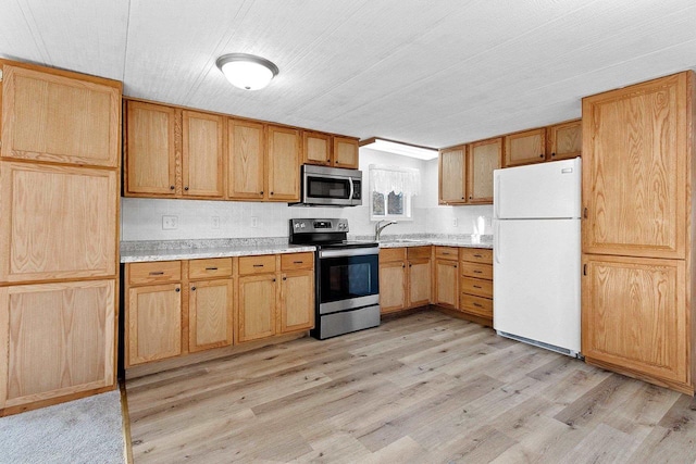 kitchen featuring appliances with stainless steel finishes, light countertops, light wood-type flooring, and a sink