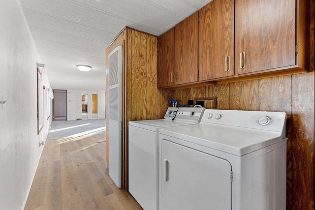 laundry room featuring washing machine and dryer, cabinet space, and light wood-style flooring