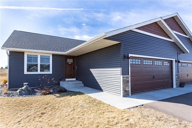 single story home with stone siding, driveway, a garage, and roof with shingles