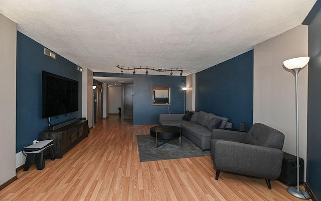 living room with a textured ceiling, track lighting, and light wood finished floors