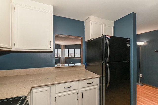 kitchen featuring light wood-style flooring, range, white cabinets, and freestanding refrigerator