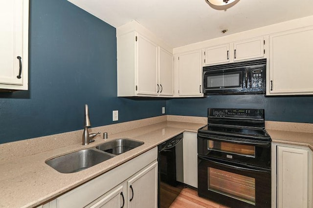 kitchen featuring black appliances, light wood-type flooring, light countertops, white cabinetry, and a sink