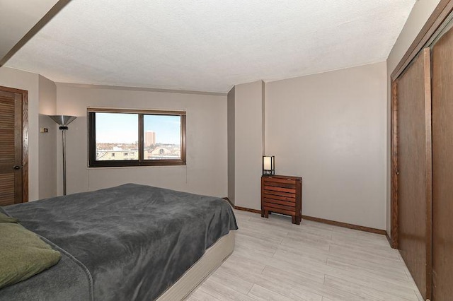 bedroom with a closet, baseboards, a textured ceiling, and light wood-style flooring