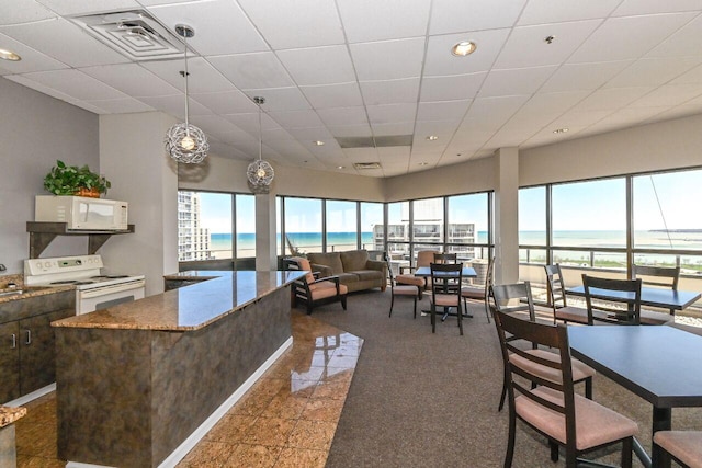 interior space with a drop ceiling, visible vents, a water view, and recessed lighting