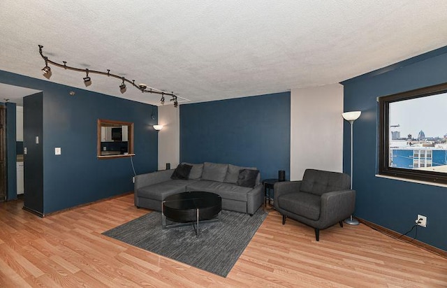 living room with a textured ceiling, baseboards, and wood finished floors