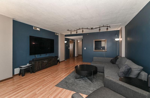 living room featuring light wood-style floors, baseboards, and a textured ceiling