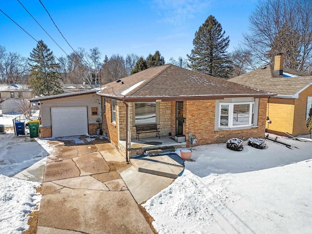 ranch-style house with driveway, roof with shingles, covered porch, a garage, and brick siding