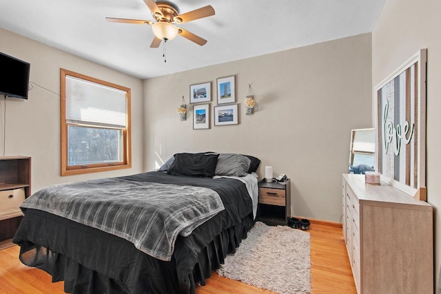 bedroom with light wood finished floors, baseboards, and a ceiling fan