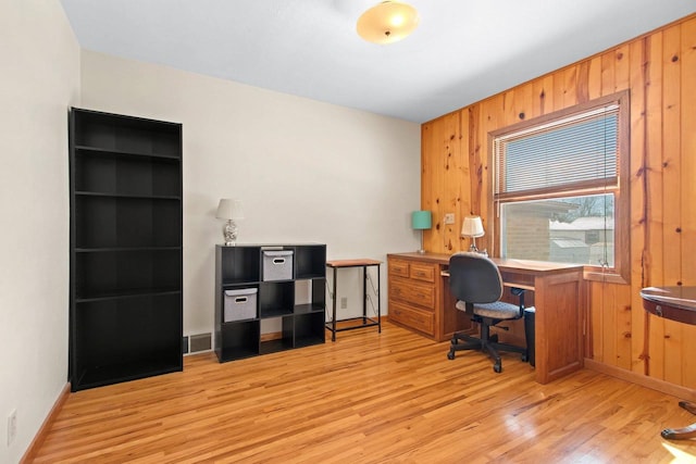 office area with light wood-style flooring, baseboards, and wood walls