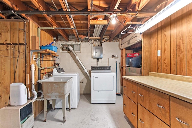 unfinished basement featuring electric panel, washing machine and dryer, and wood walls