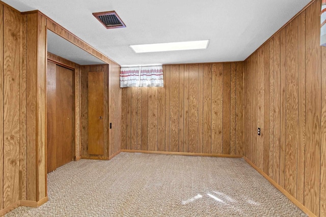 below grade area with visible vents, carpet flooring, and wood walls