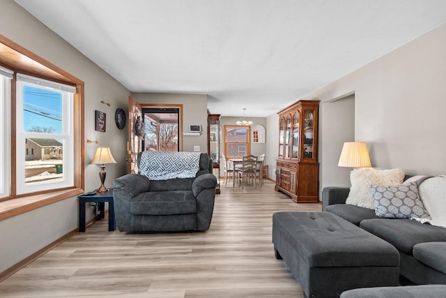 living area with a notable chandelier, baseboards, and light wood-type flooring