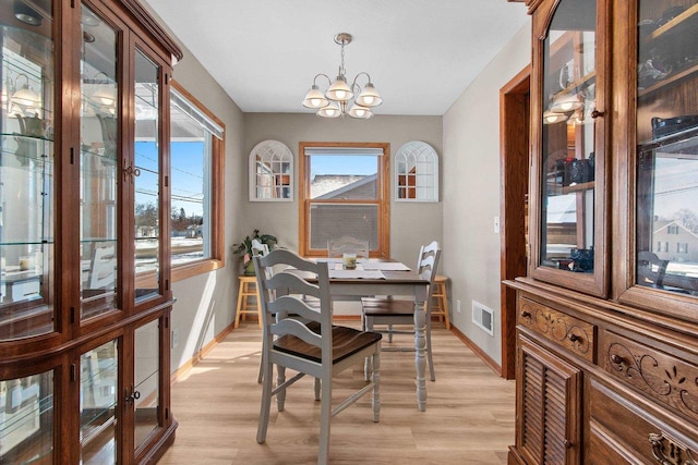 dining space with visible vents, baseboards, an inviting chandelier, and light wood finished floors