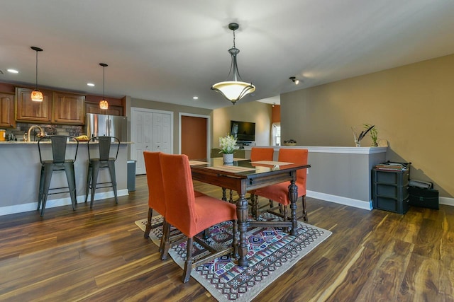 dining room with dark wood finished floors, recessed lighting, and baseboards