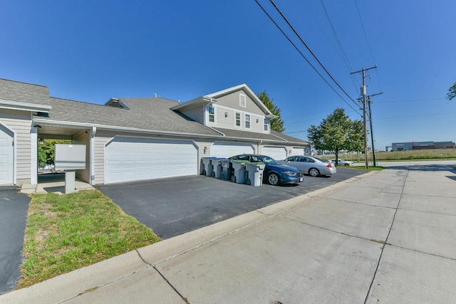 exterior space with driveway and a shingled roof