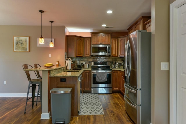 kitchen with a peninsula, a sink, decorative backsplash, stainless steel appliances, and a kitchen breakfast bar