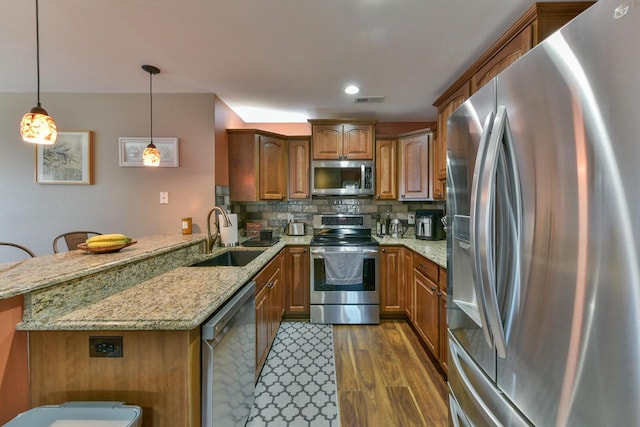 kitchen with backsplash, dark wood-type flooring, appliances with stainless steel finishes, a peninsula, and a sink