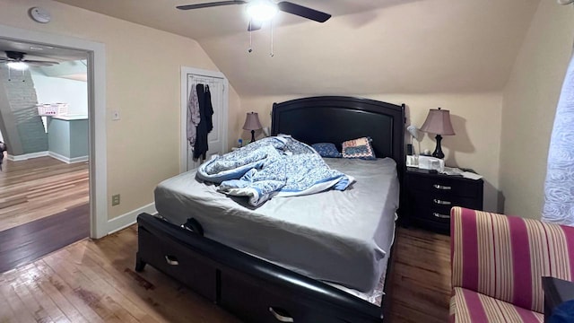 bedroom with a ceiling fan, wood finished floors, a closet, baseboards, and vaulted ceiling