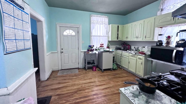 kitchen with stainless steel microwave, dark wood-style floors, and green cabinetry