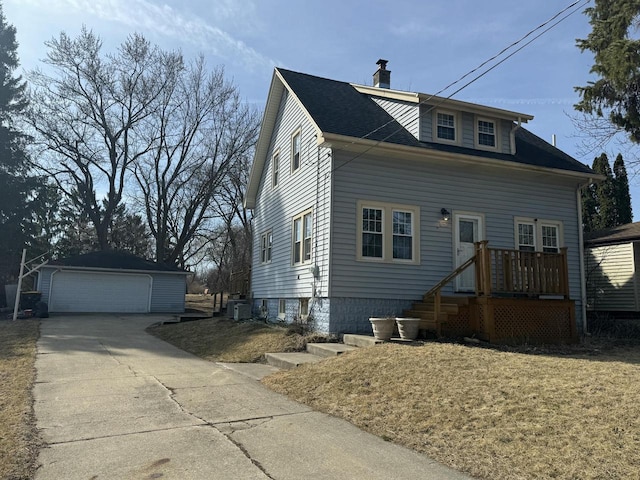 view of front of home with a shingled roof, a detached garage, cooling unit, a chimney, and an outdoor structure